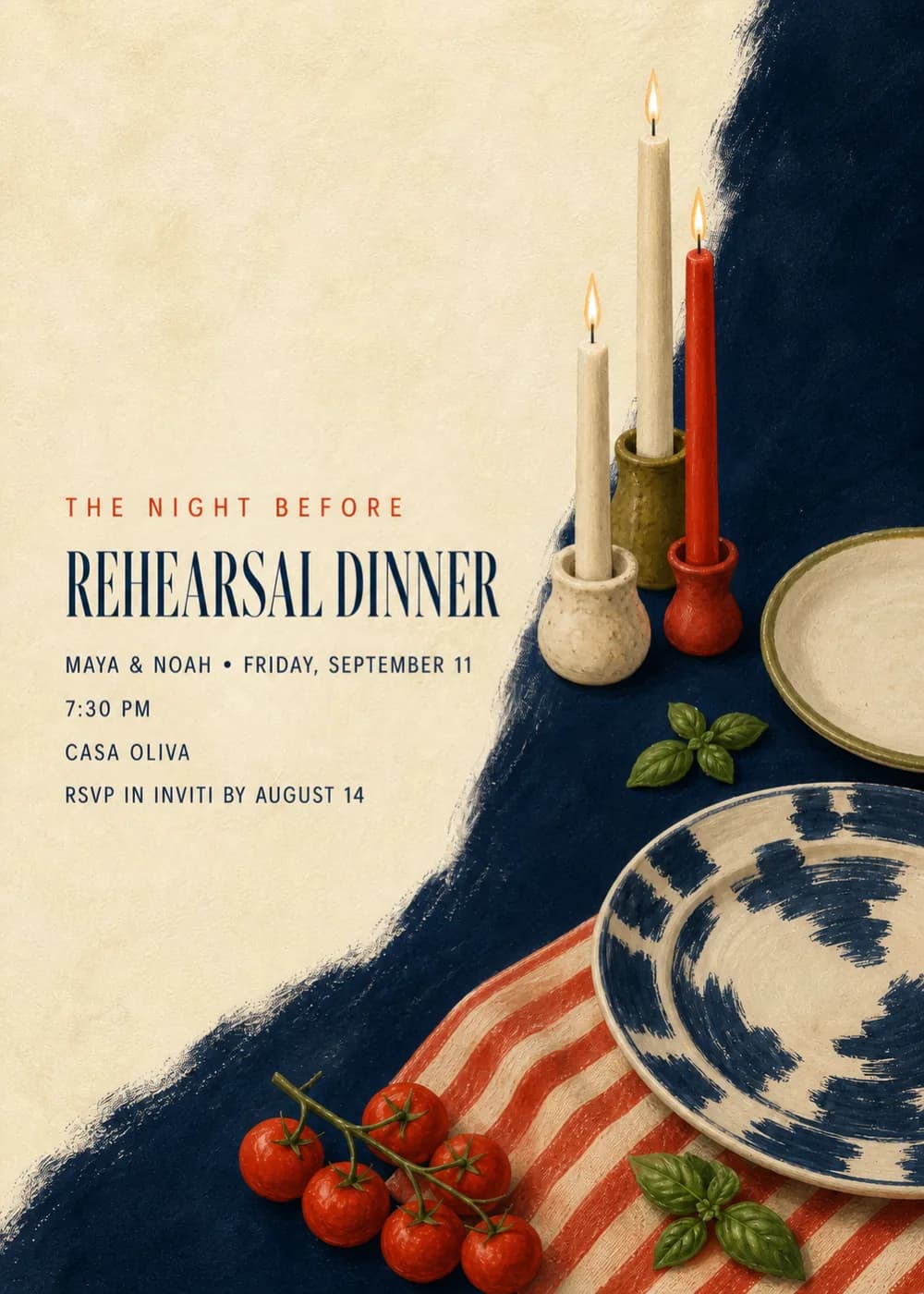 The Night Before rehearsal dinner invitation with lit taper candles in ceramic holders, blue ikat plates, cherry tomatoes and basil on a red striped cloth over navy